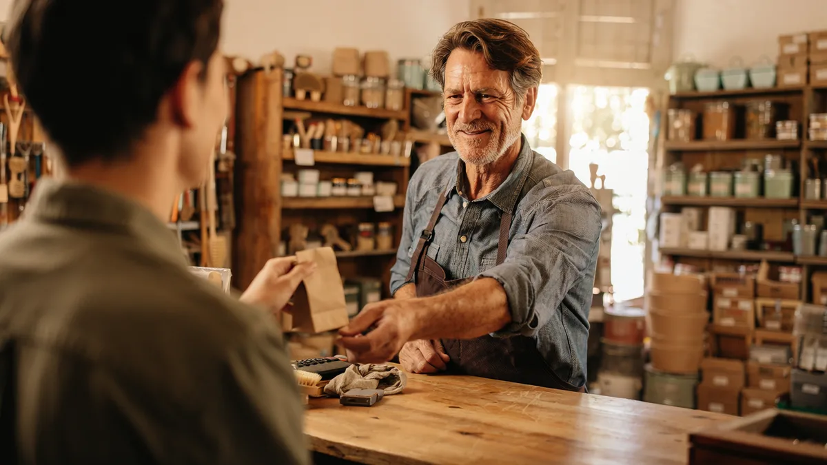 Foto generata con IA: un negoziante sorridente consegna un sacchetto a un cliente al bancone